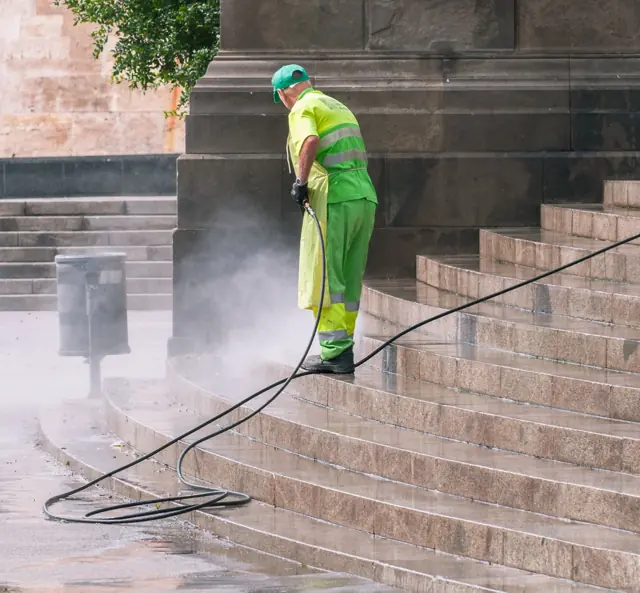 Technician pressure washing stone stairs